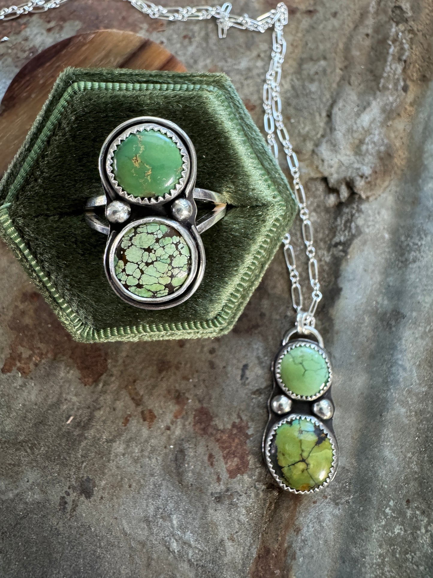 Silver ring and necklace with green turquoise stones on a textured surface